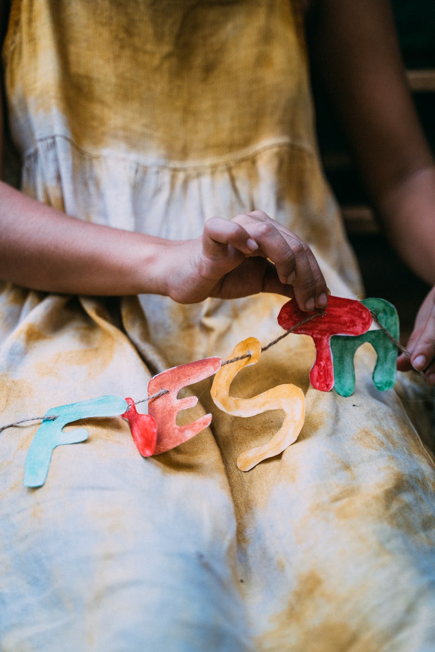 person putting letter cutouts on string